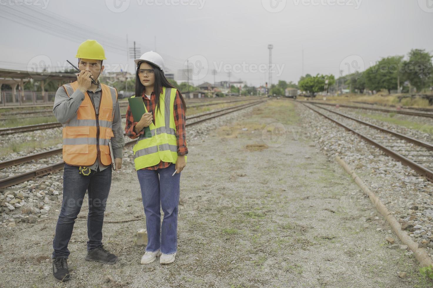 dos ingeniero trabajando a tren estación, trabajo juntos felizmente, ayuda cada otro analizar el problema consultar acerca de desarrollo pautas foto