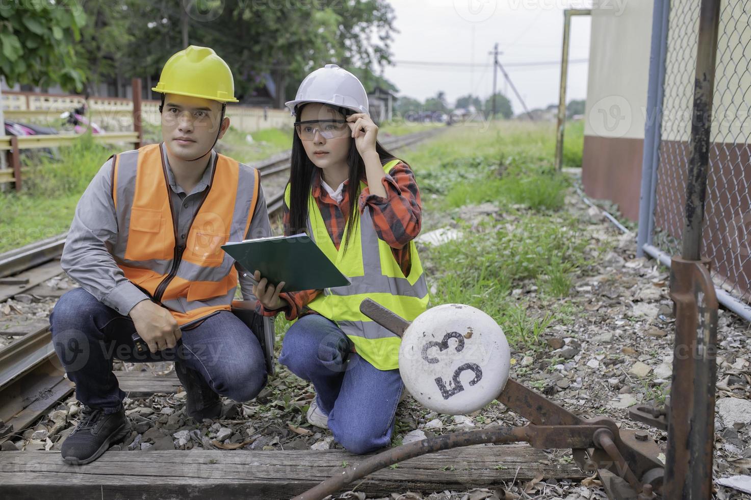 dos ingeniero trabajando a tren estación, trabajo juntos felizmente, ayuda cada otro analizar el problema consultar acerca de desarrollo pautas foto