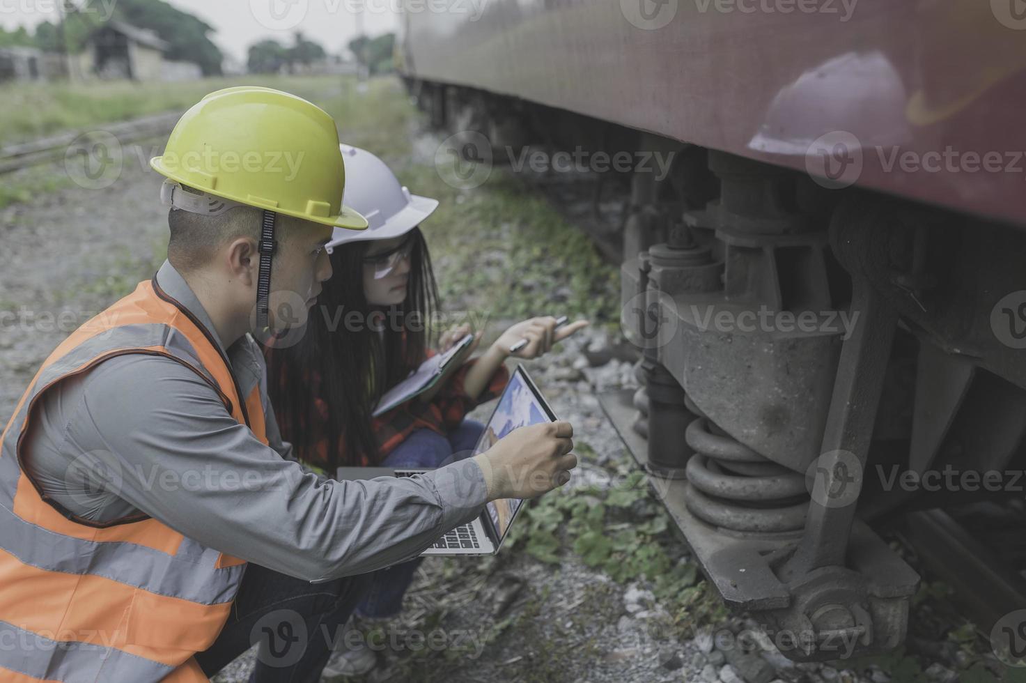 dos ingeniero trabajando a tren estación, trabajo juntos felizmente, ayuda cada otro analizar el problema consultar acerca de desarrollo pautas foto