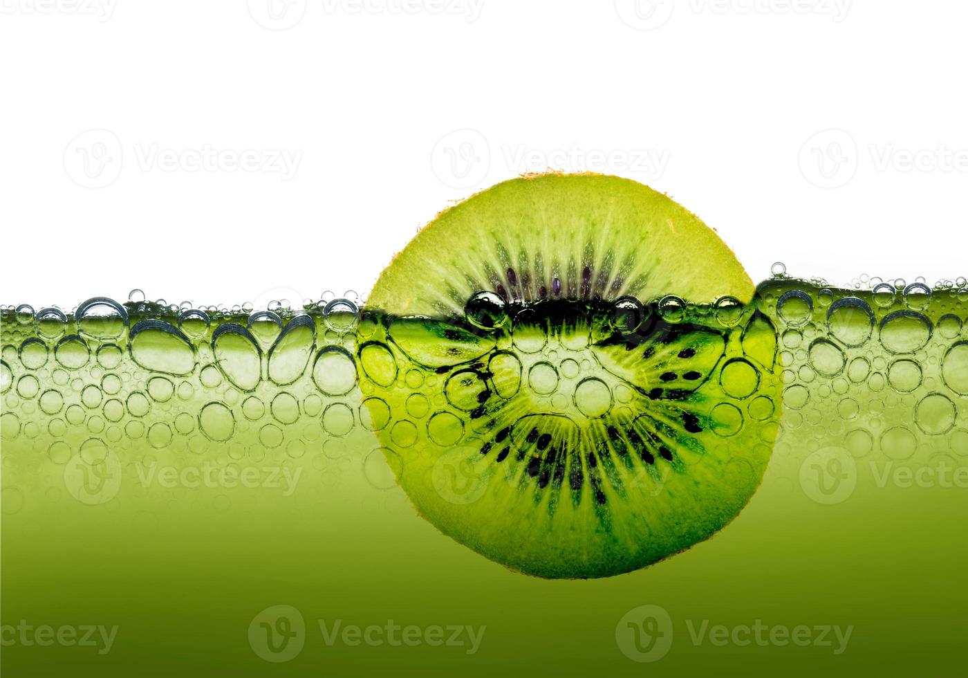 close up of sliced Kiwi fruit in clear green water with air bubbles photo