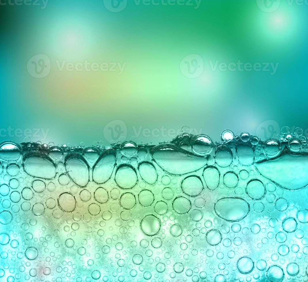 Bubbles in a clear green liquid with a blurred blue-green background and bokeh photo