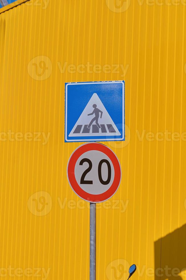 Vertical frame, traffic signs on against a bright yellow warehouse wall from a profiled metal wall, background ideas for a screen or design articles photo