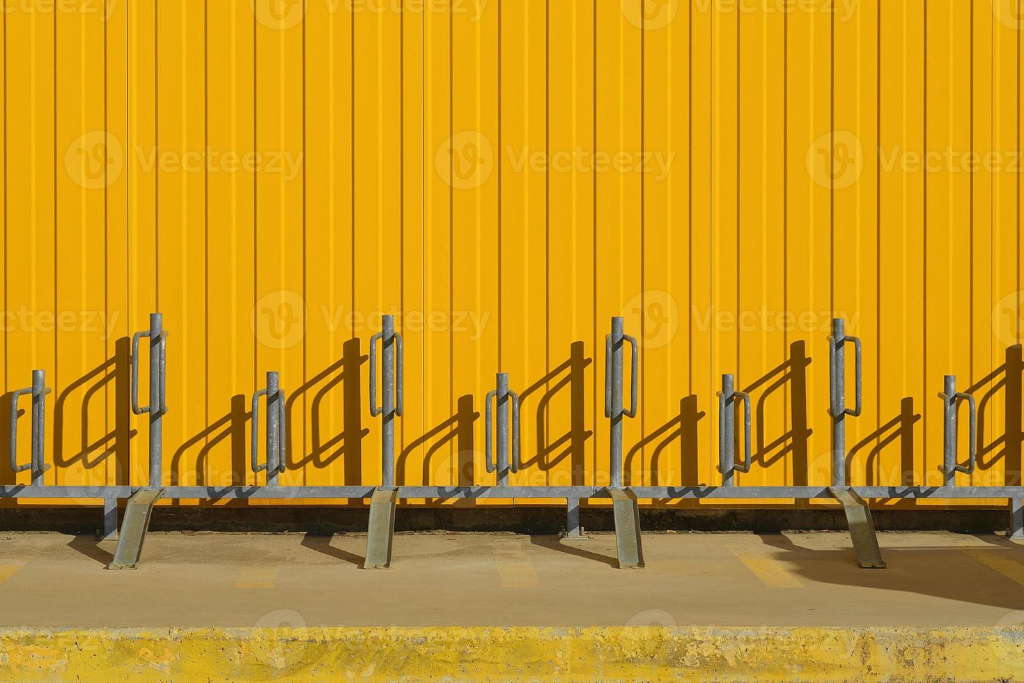 Bicycle parking near a bright yellow profiled metal wall, fence or warehouse idea, background for a screen or design articles photo