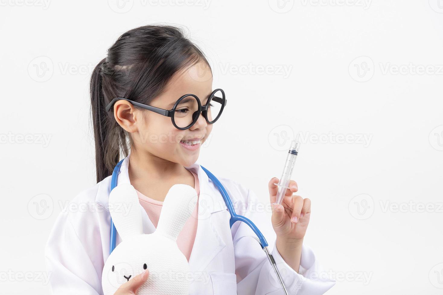 Asia pequeño niña jugando médico aislado en blanco foto