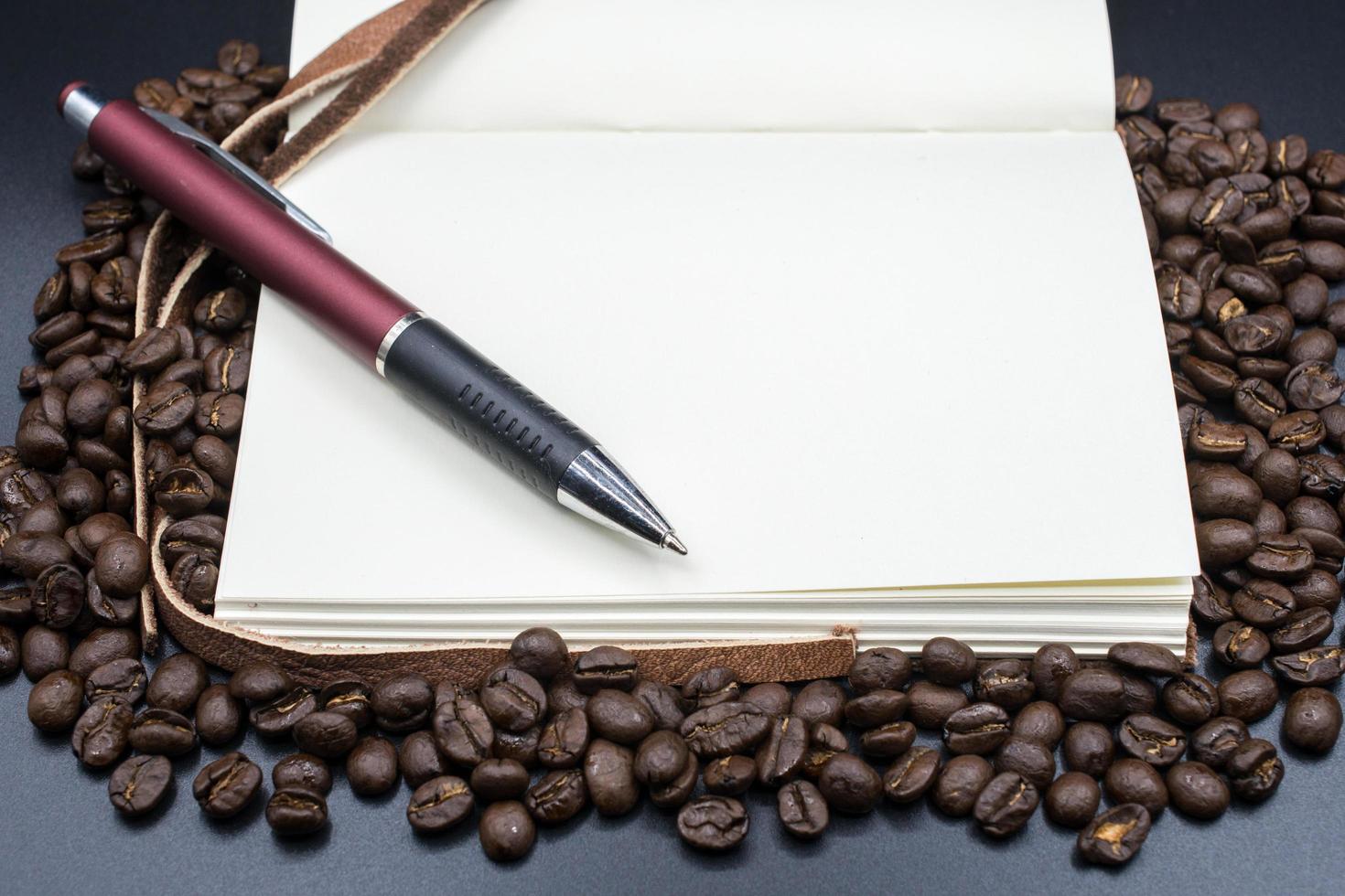 A book open the empty page on the roasted coffee beans with isolated black background. photo