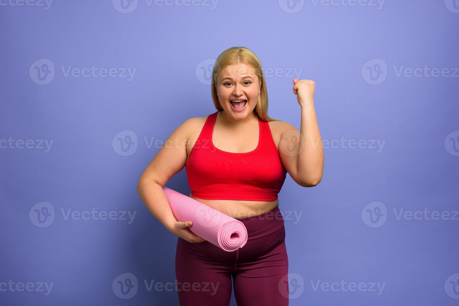 Fat girl does gym at home. satisfied and successfully expression. purple background. photo