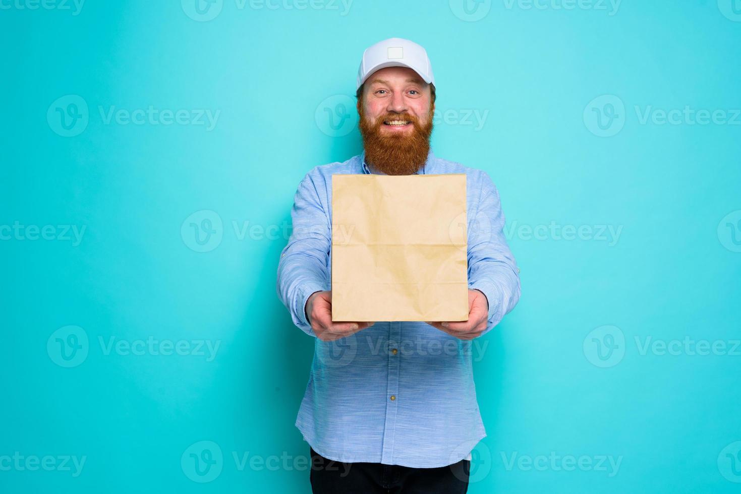 Deliveryman with happy expression is ready to deliver a food package photo