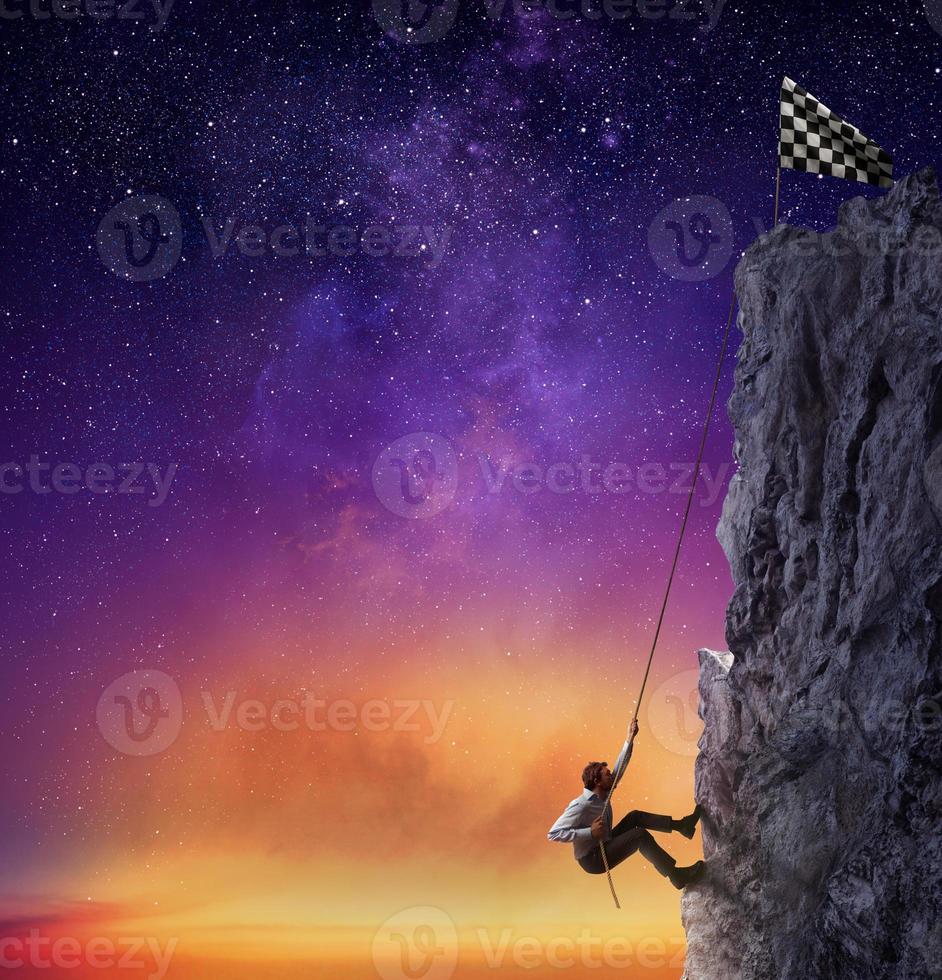 Businessman climb a mountain to get the flag. Achievement business goal and difficult career concept photo