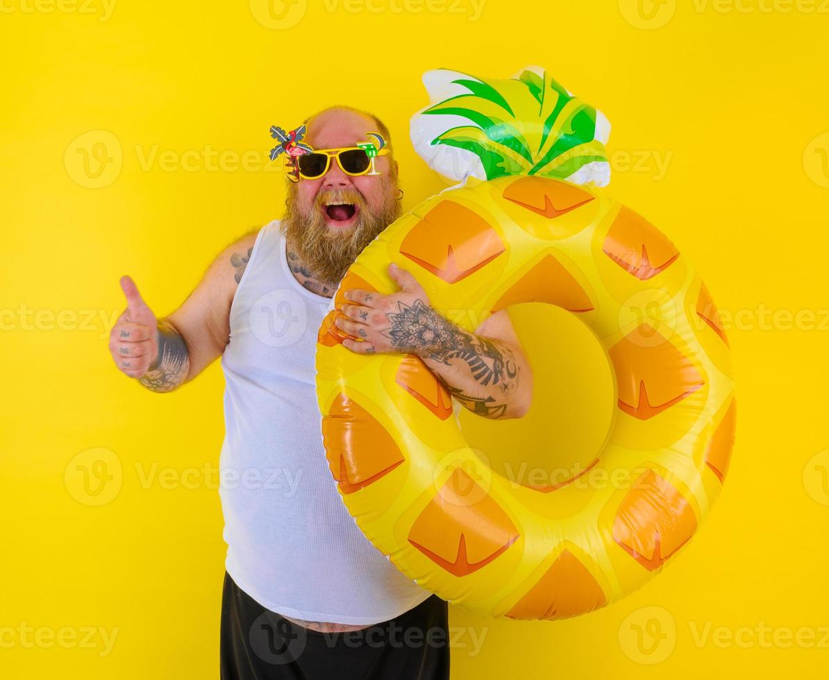 Fat happy man with wig in head is ready to swim with a donut lifesaver photo