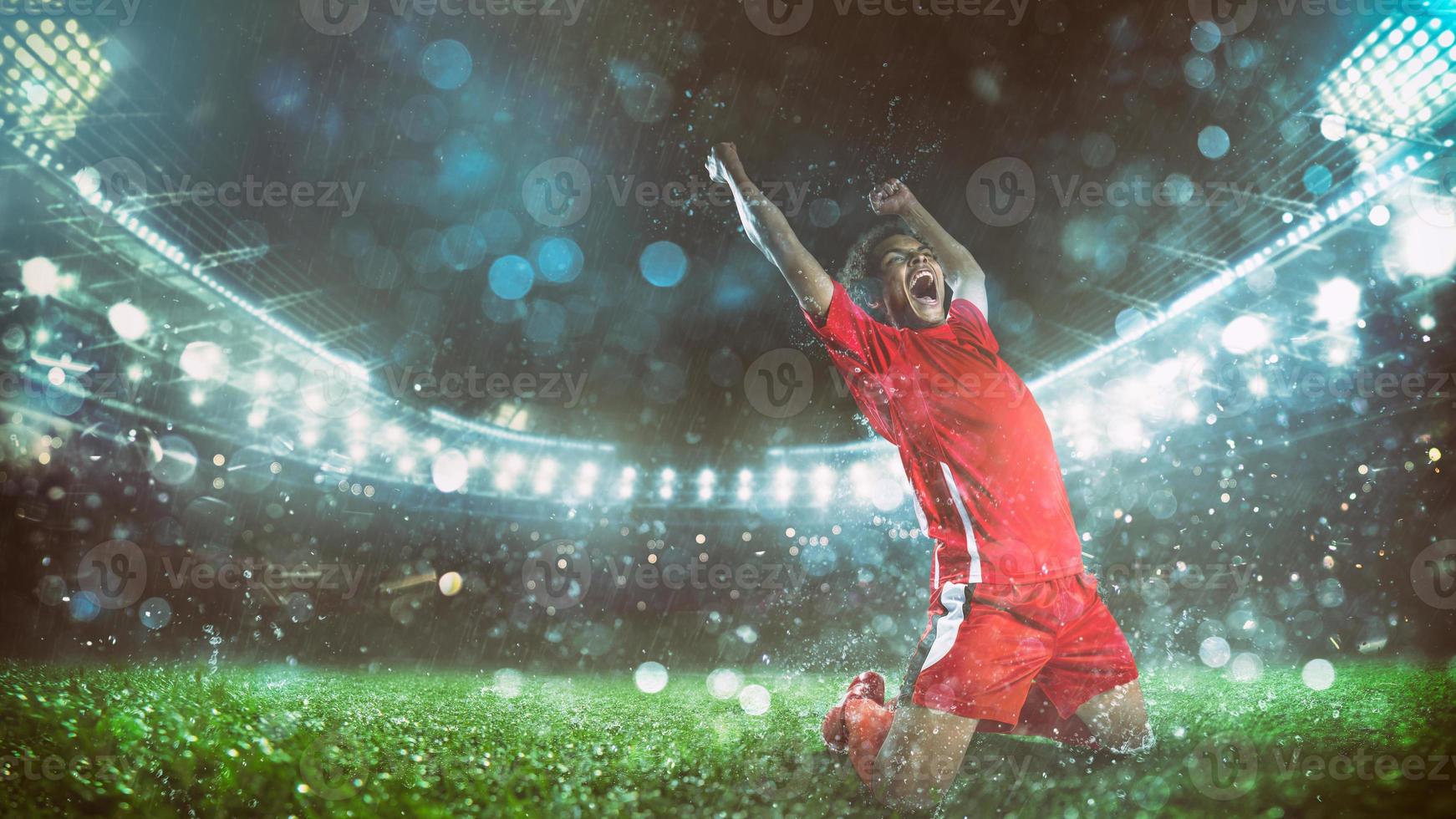 Soccer striker in red uniform rejoices for the victory at the stadium photo