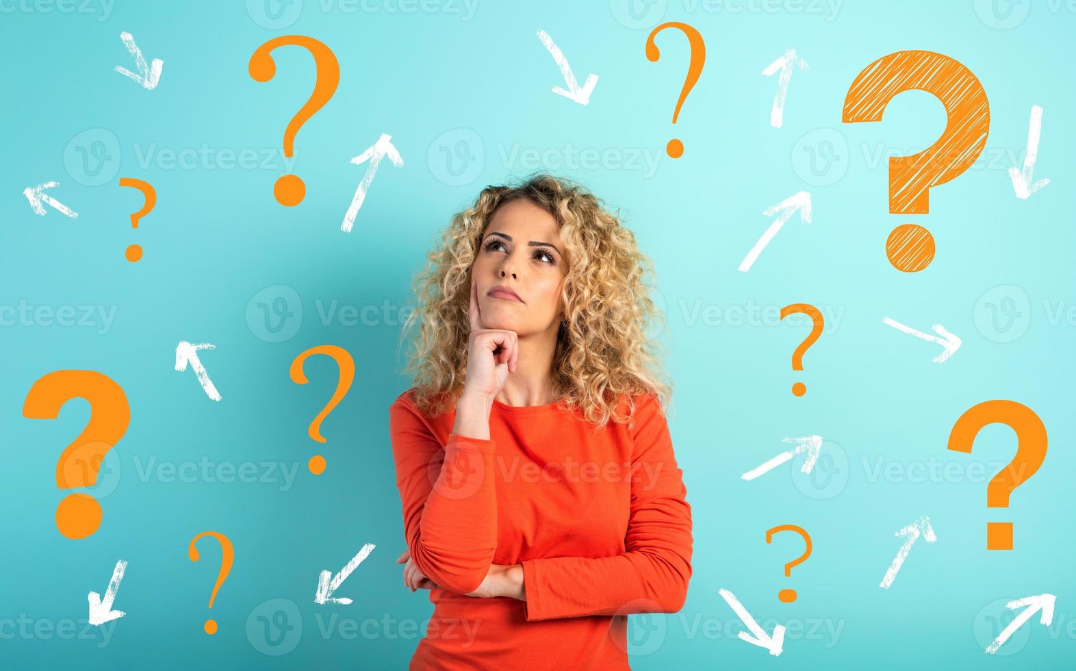 Confused and pensive expression of a girl with many questions . cyan colored background photo