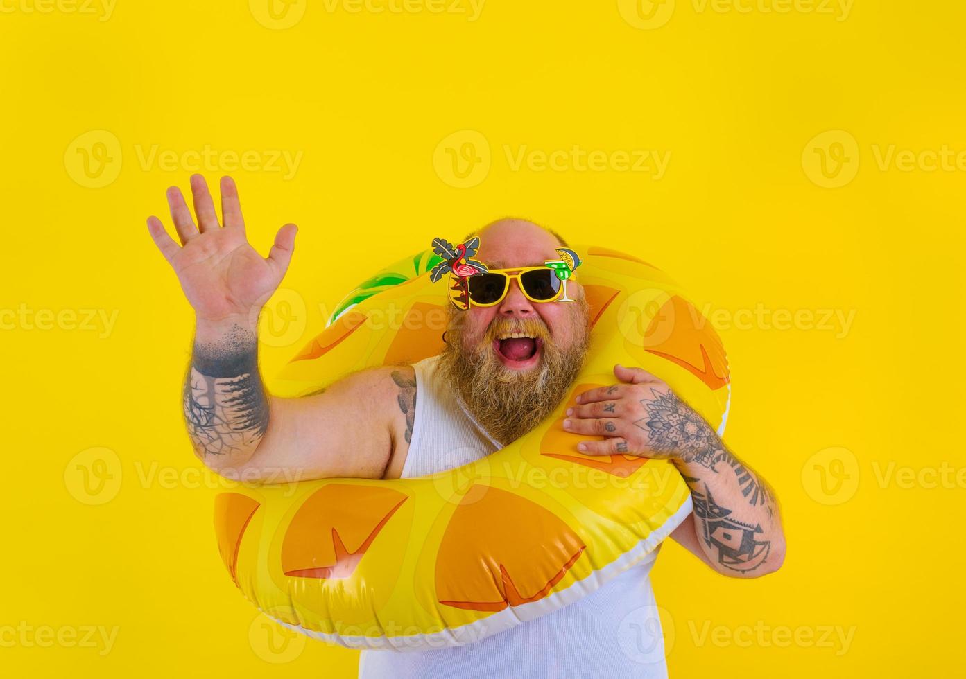 Fat happy man with wig in head is ready to swim with a donut lifesaver photo