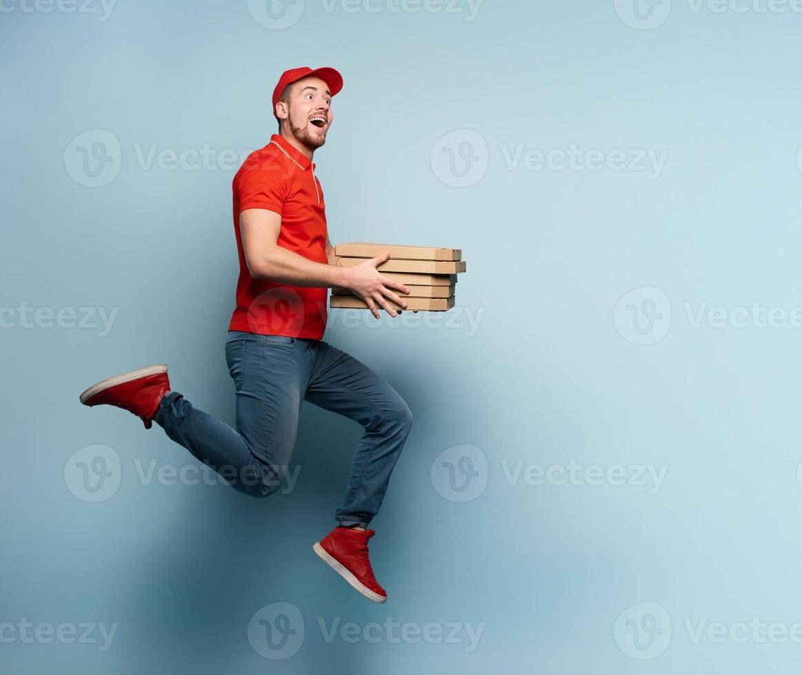 Courier runs fast to deliver quickly pizzas. Cyan background photo