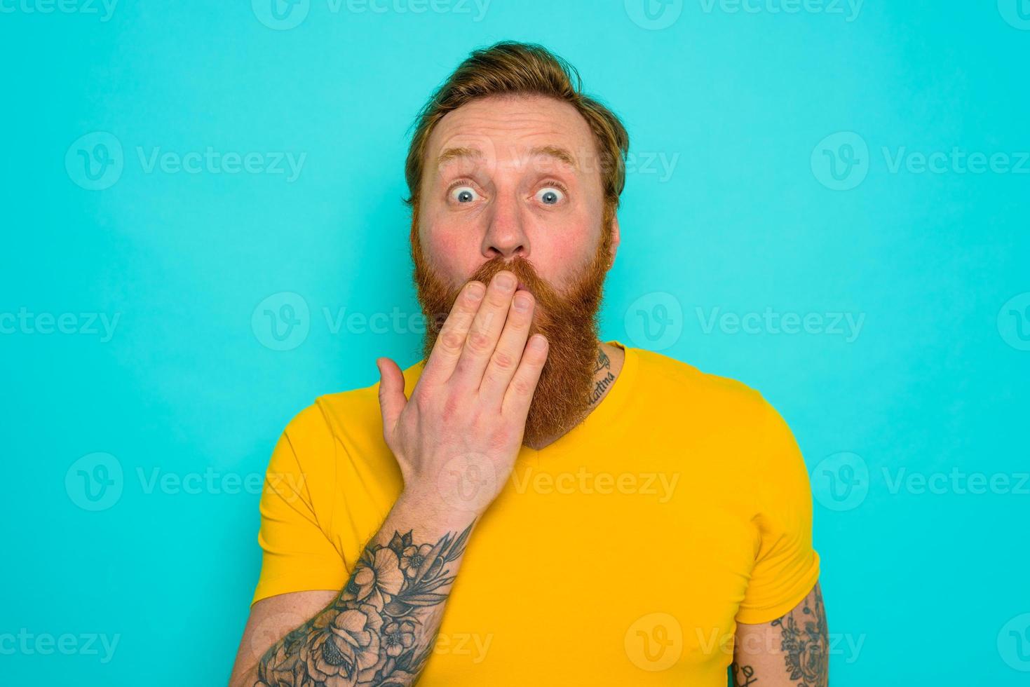 Man with yellow t-shirt and beard is worried and preoccupied photo