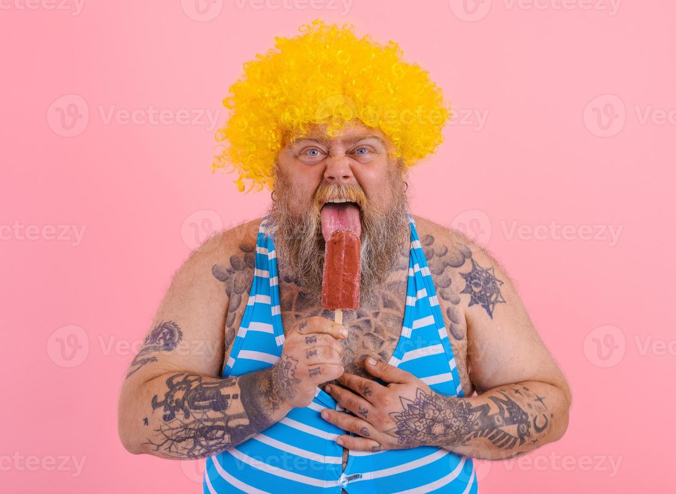 Fat hungry man with beard and wig eats a popsicle photo