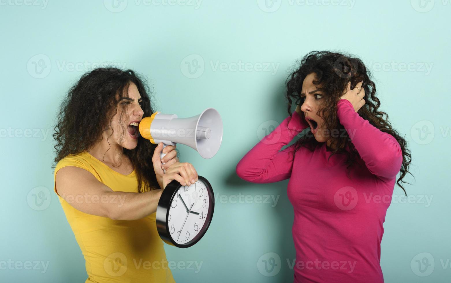 Woman screams with loudspeaker to a friend because is too late. angry expression. cyan background photo