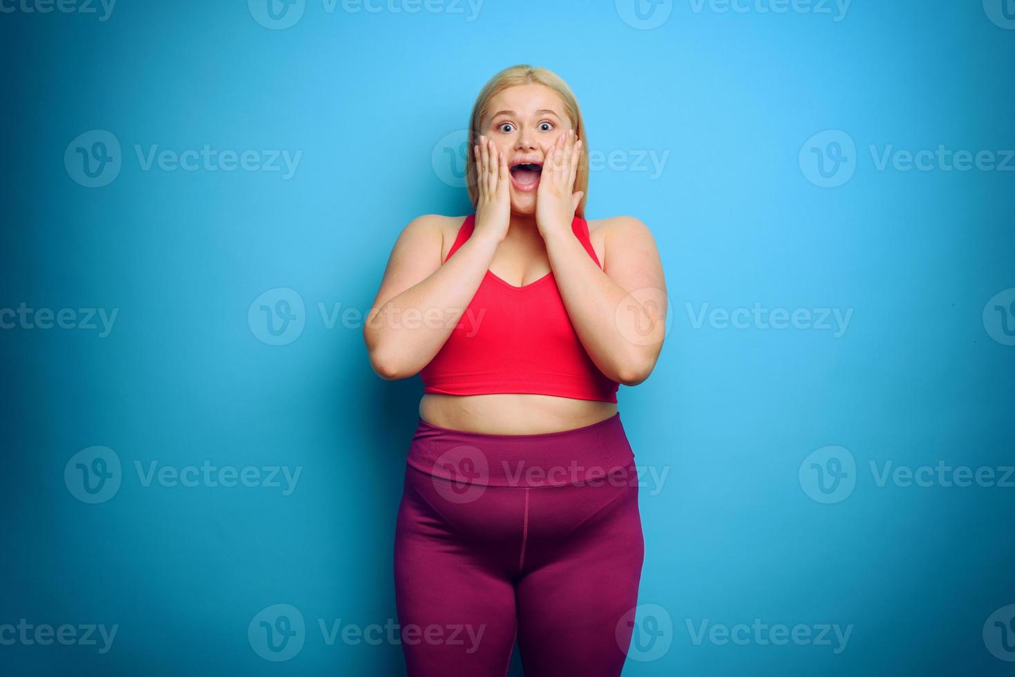 Fat woman with shocked and surprised expression. Cyan background photo