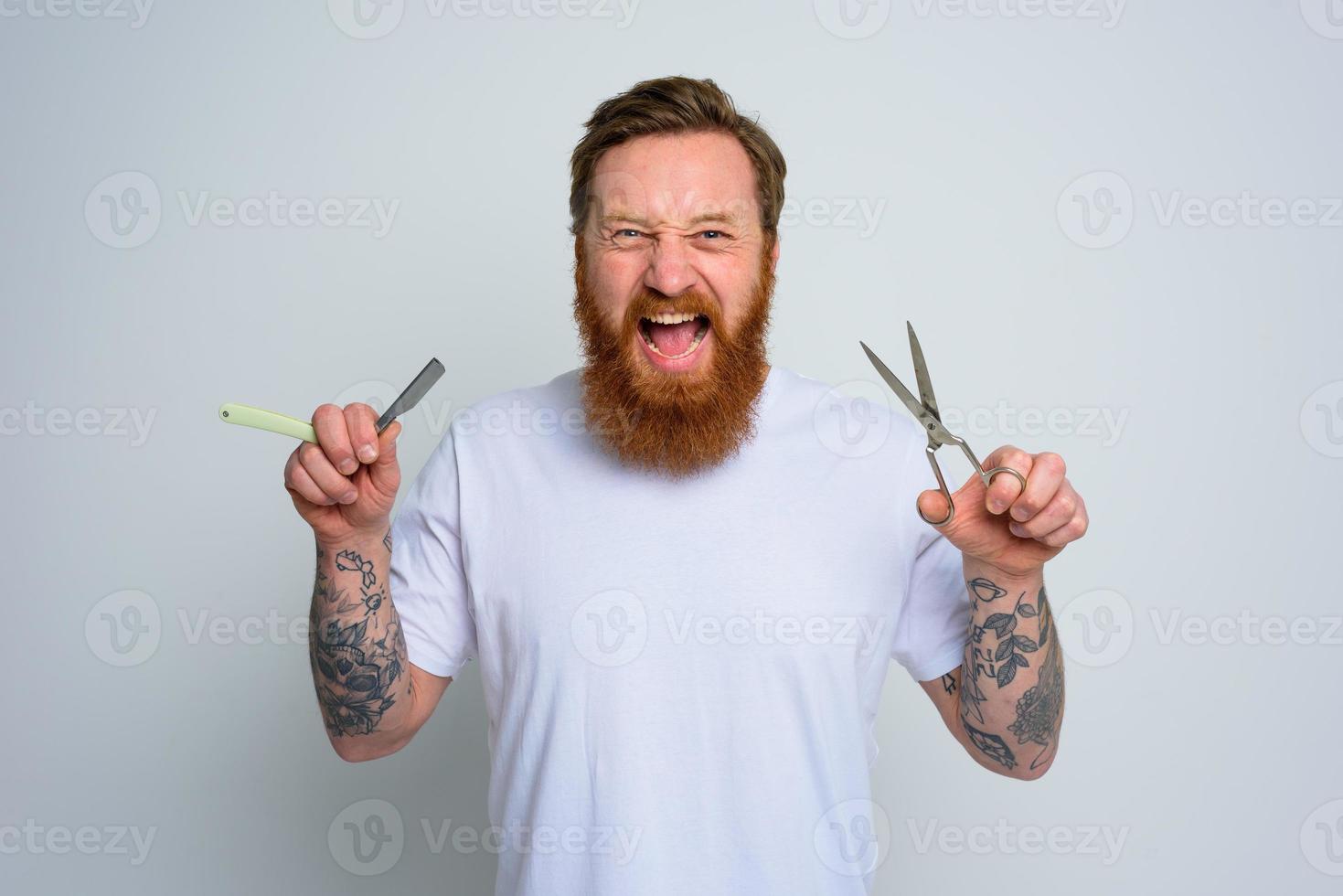 Aggressive man with scissors and blade is ready to cut the beard photo