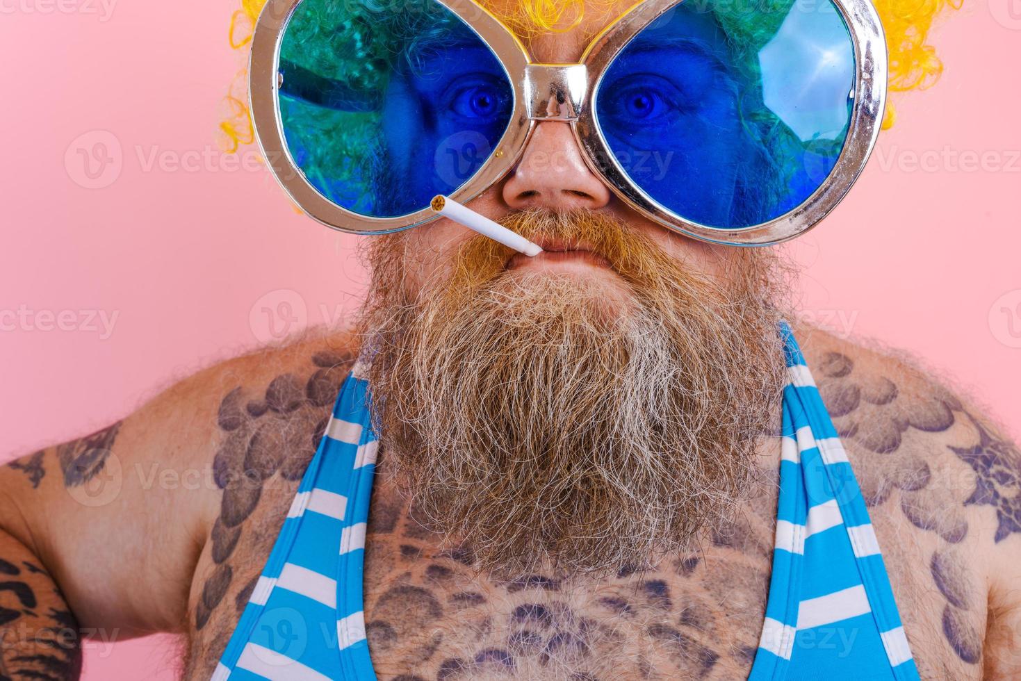 Fat angry man with beard and wig smokes cigarettes photo