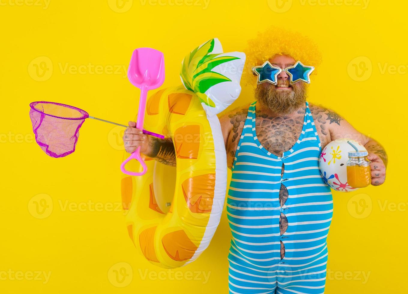 Fat happy man with wig in head is ready to swim with a donut lifesaver photo