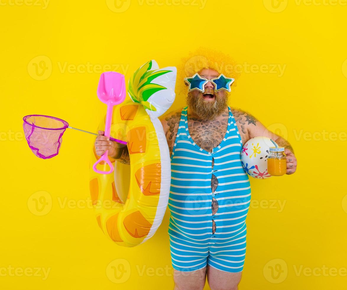 Fat happy man with wig in head is ready to swim with a donut lifesaver photo