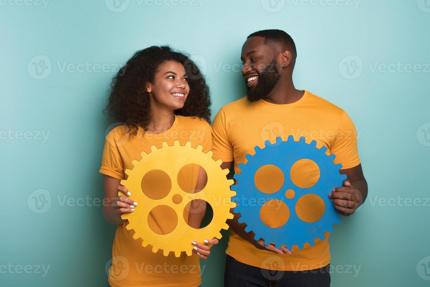 Couple with gears in hand over light blue background. Concept of integration, union and partnership photo