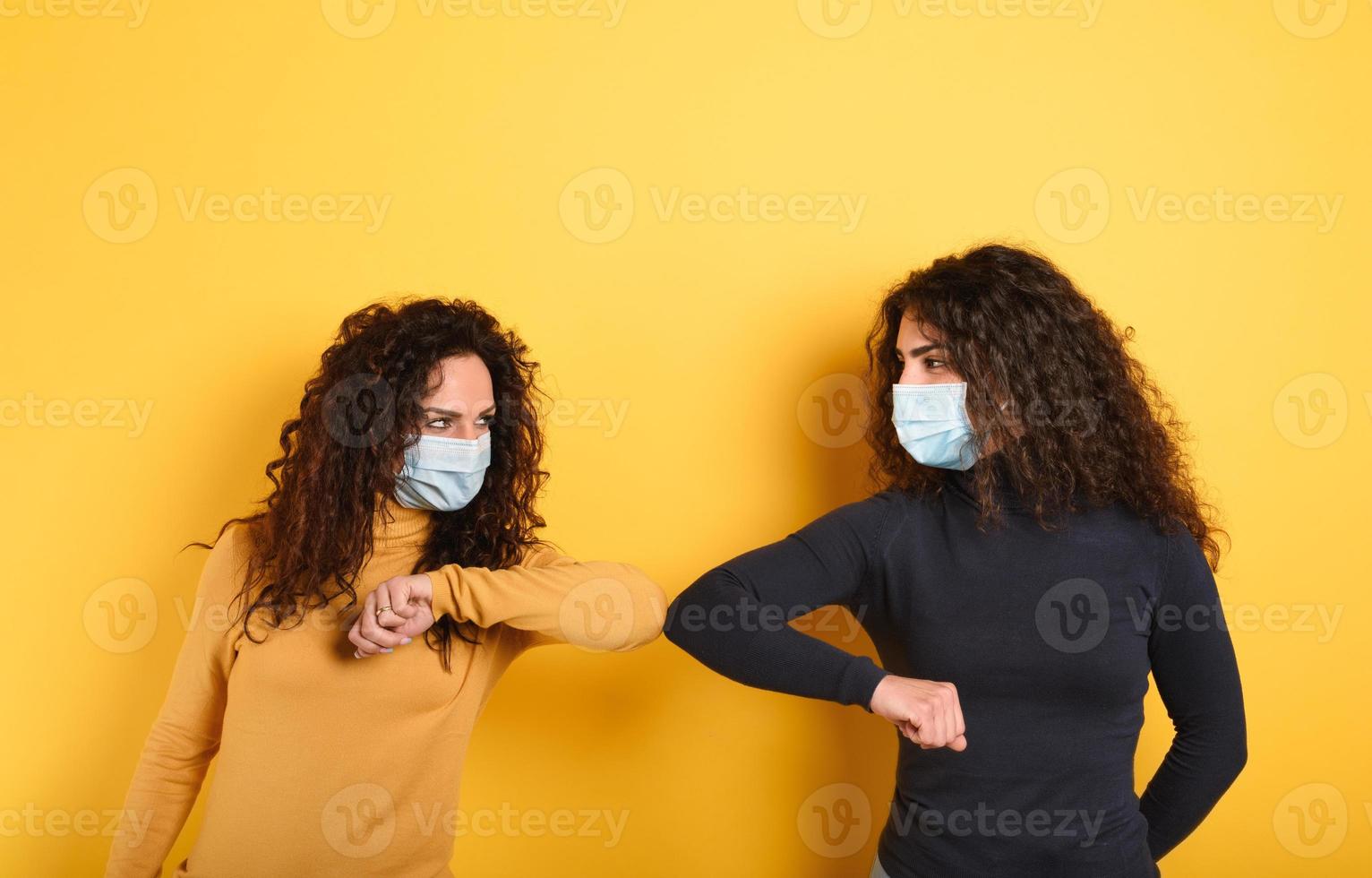 Friends stay away to avoid contact and contagion of the virus. Concept of codiv-19 rules to avoid pandemic. yellow background photo