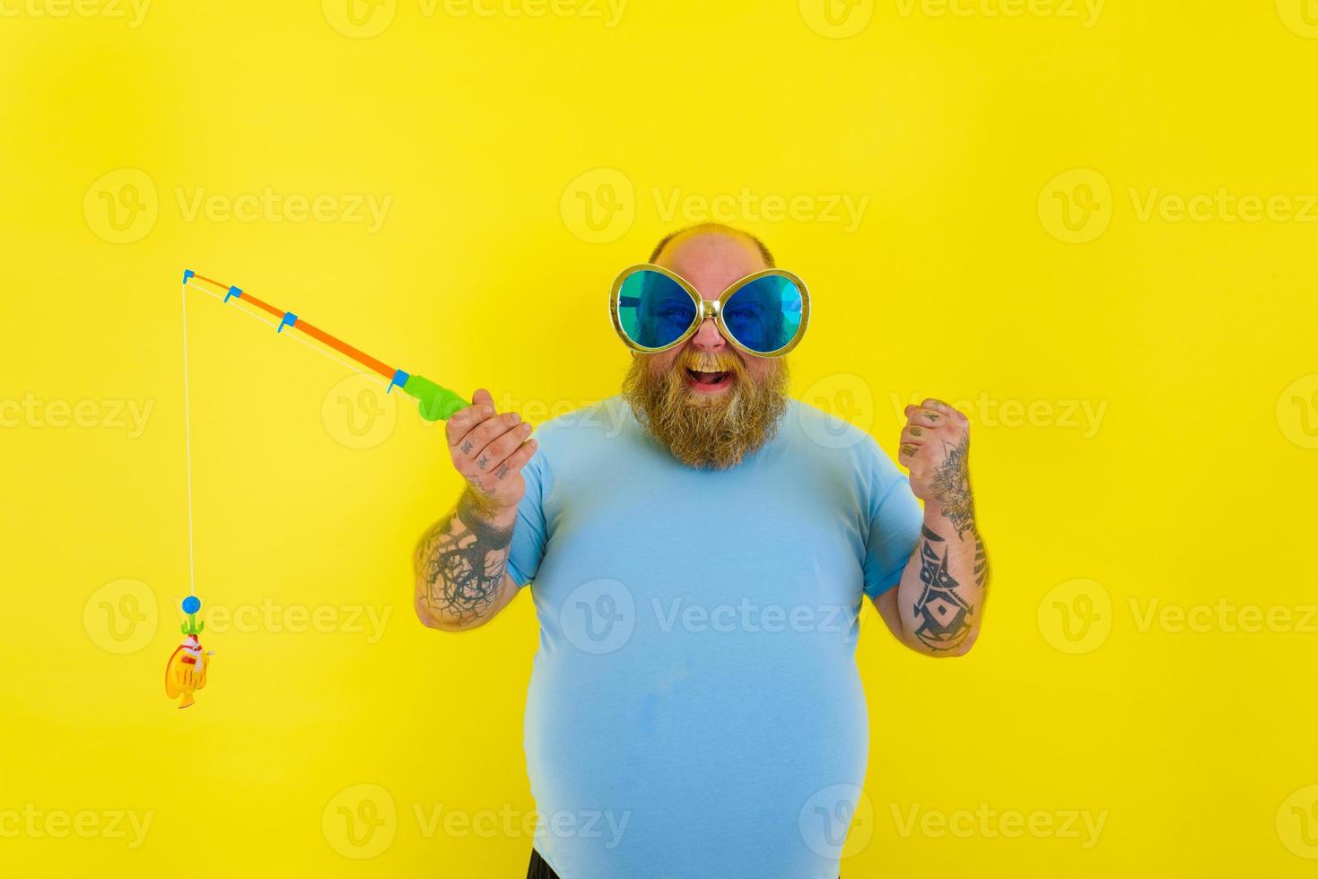 Fat man with beard and sunglasses have fun with the fishing rod photo