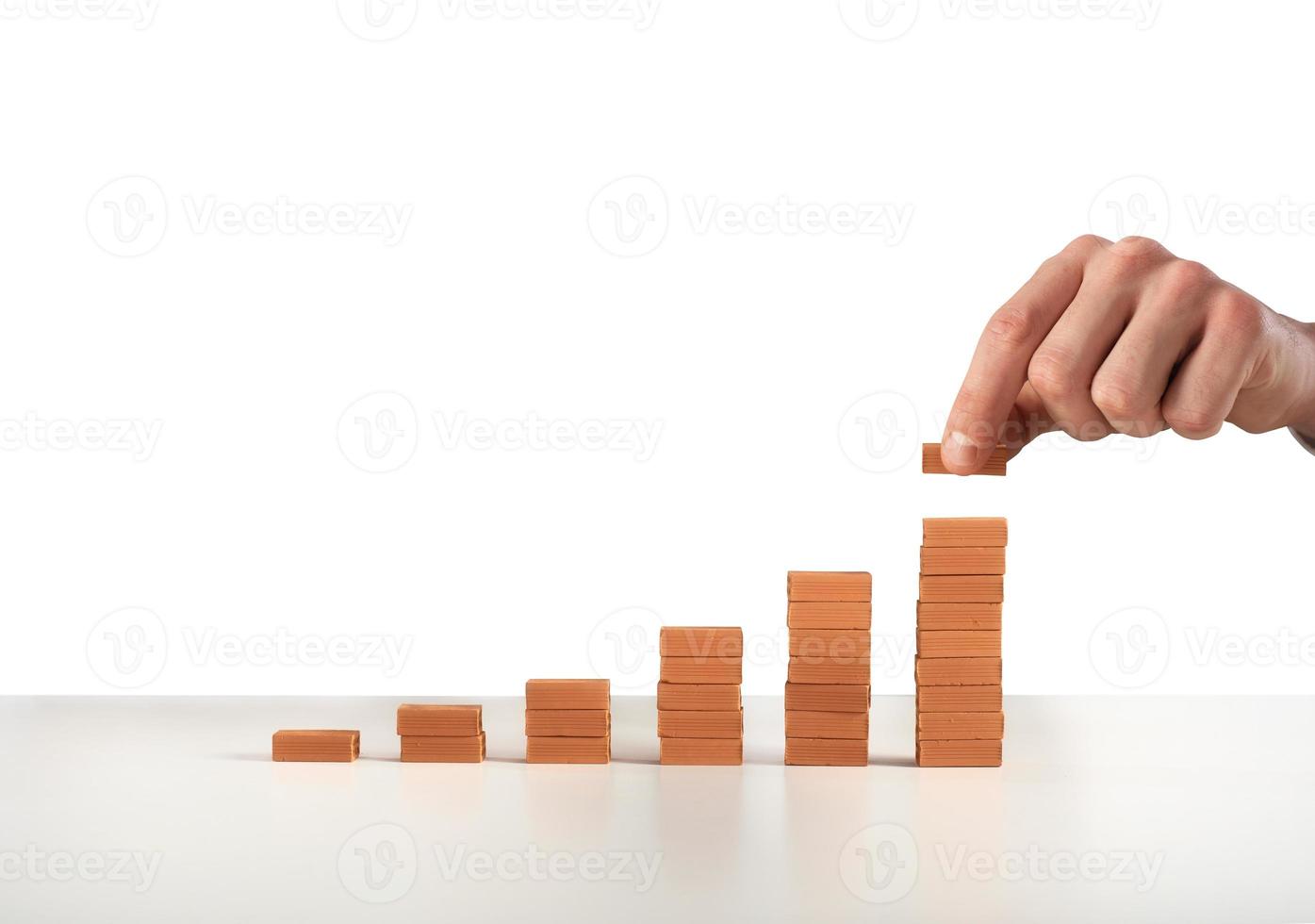 Businessman puts a brick on a bricks pile. Concept of growing statistics and success photo