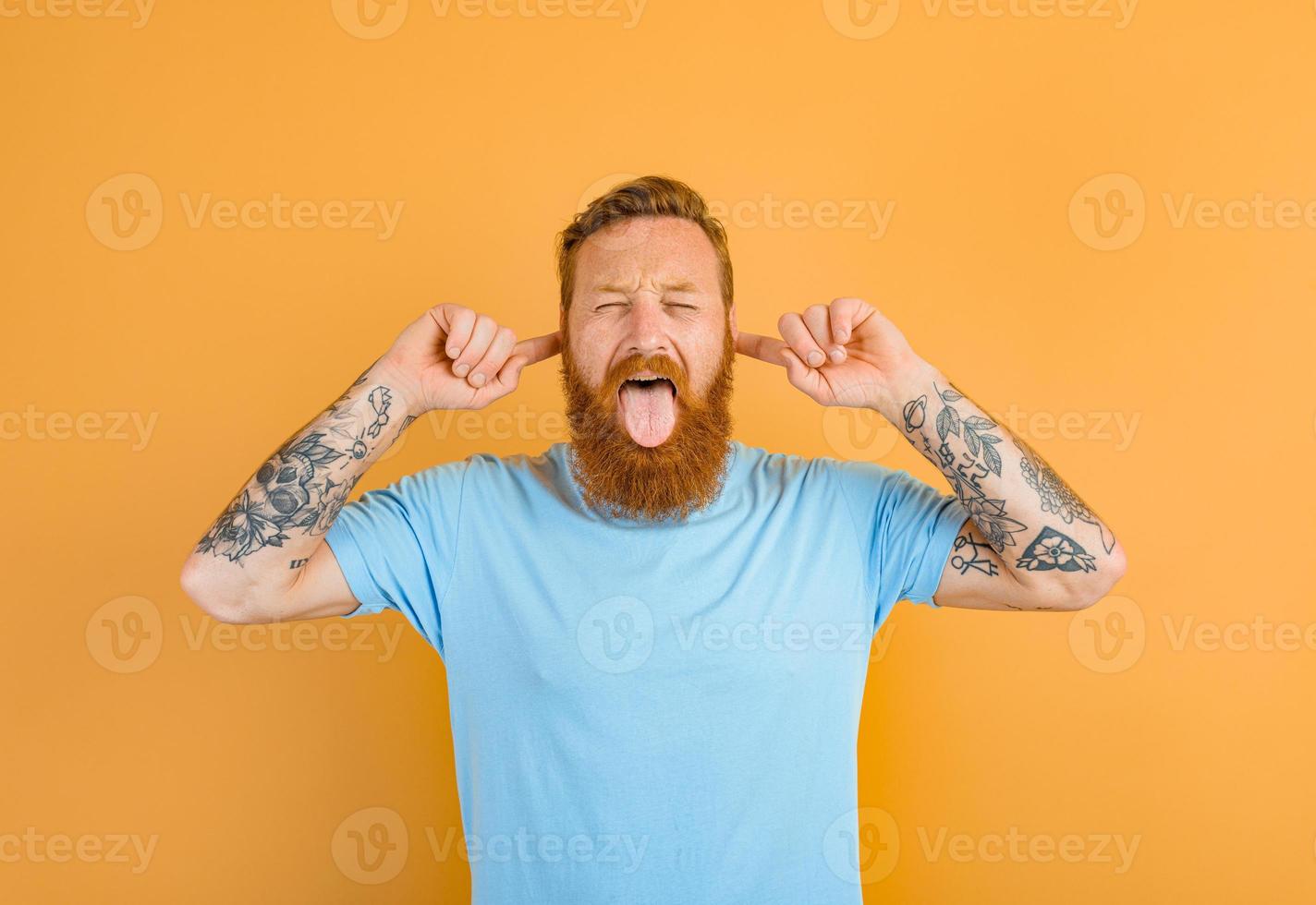 Man with beard and tattoo sticks his tongue out photo