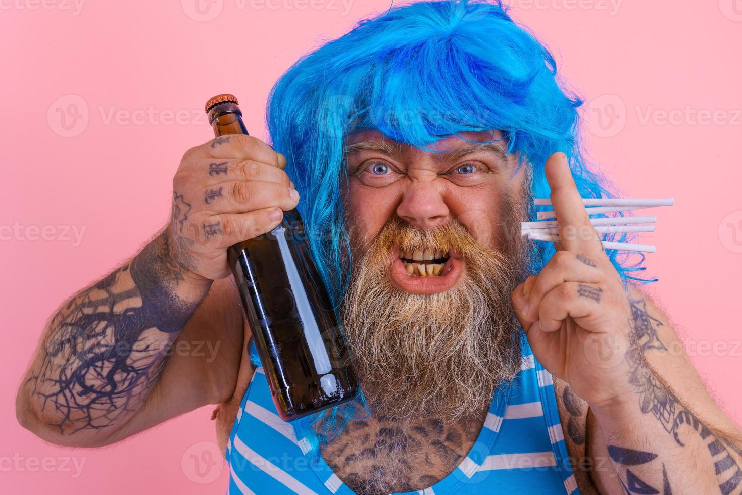 Fat man with beard and wig smokes cigarettes and drinks beer photo