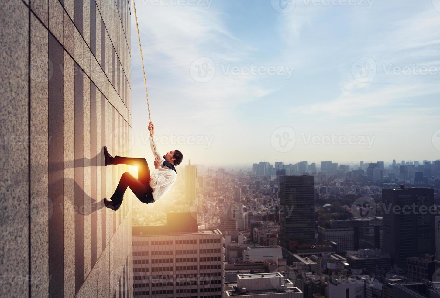 Businessman climbs a building with a rope. Concept of determination photo