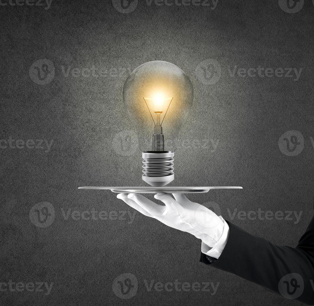 Waiter that holds a tray with a lightbulb. Concept big idea photo