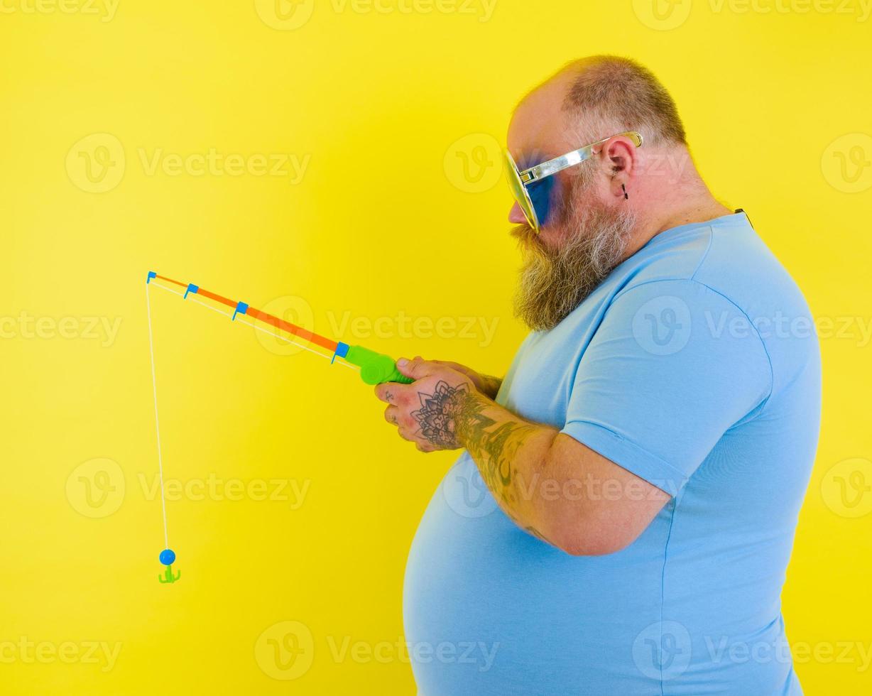 Fat man with beard and sunglasses is unhappy with the fishing rod photo
