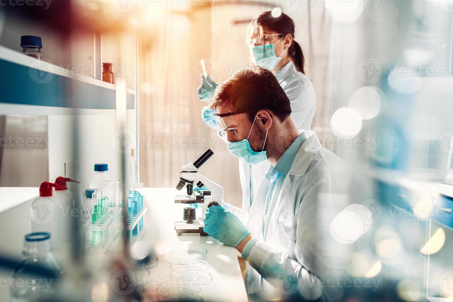 Doctor in the laboratory analyzes samples of codiv-9 under a microscope photo