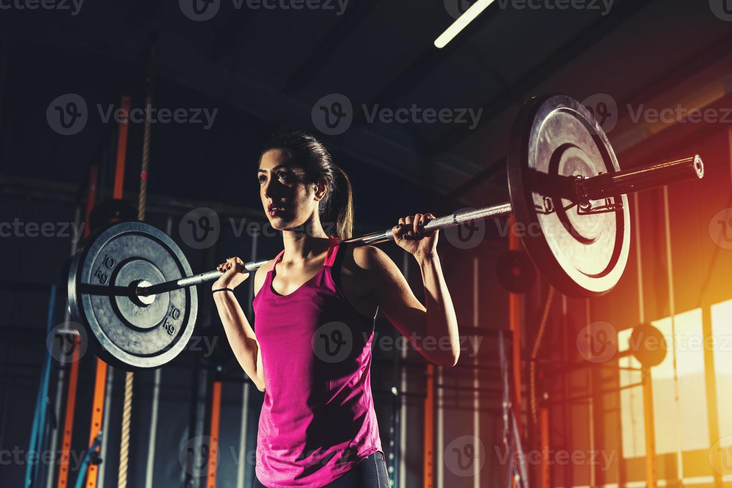 Athletic girl works out at the gym with a barbell photo