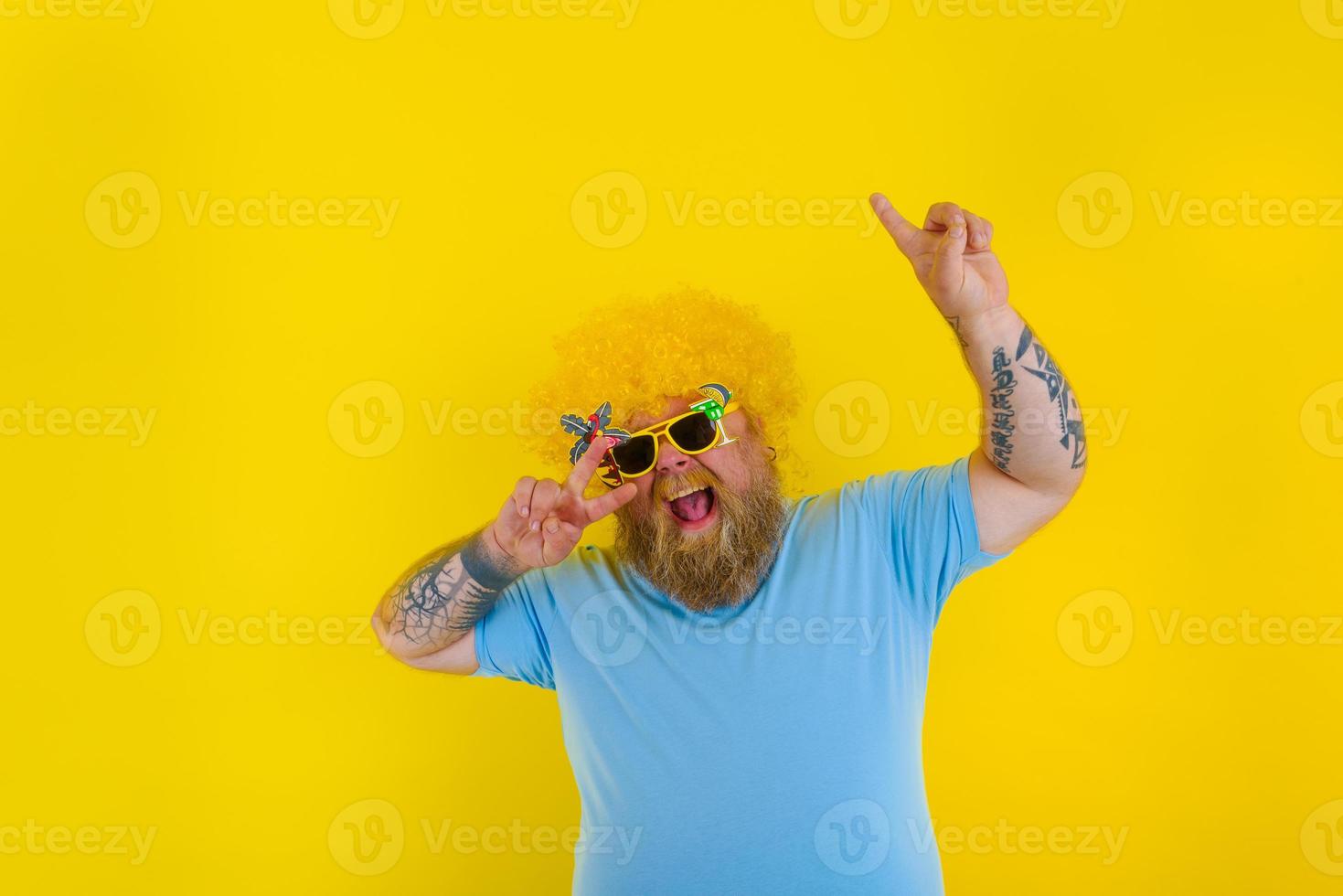 Fat man with wig in head and sunglasses dances photo