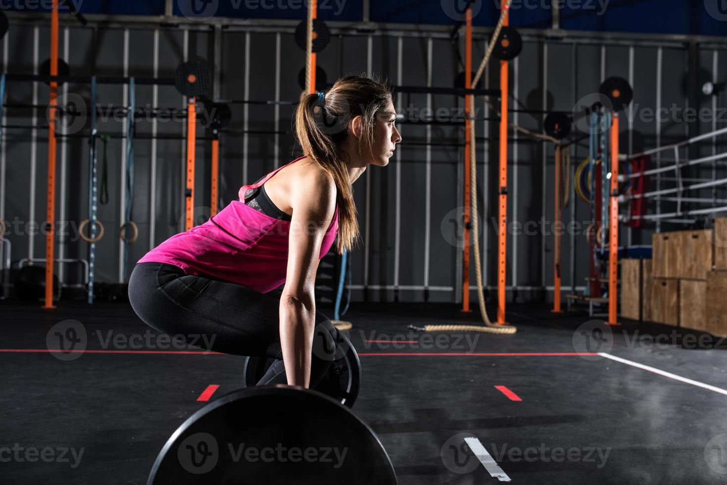 Athletic girl works out at the gym with a barbell photo