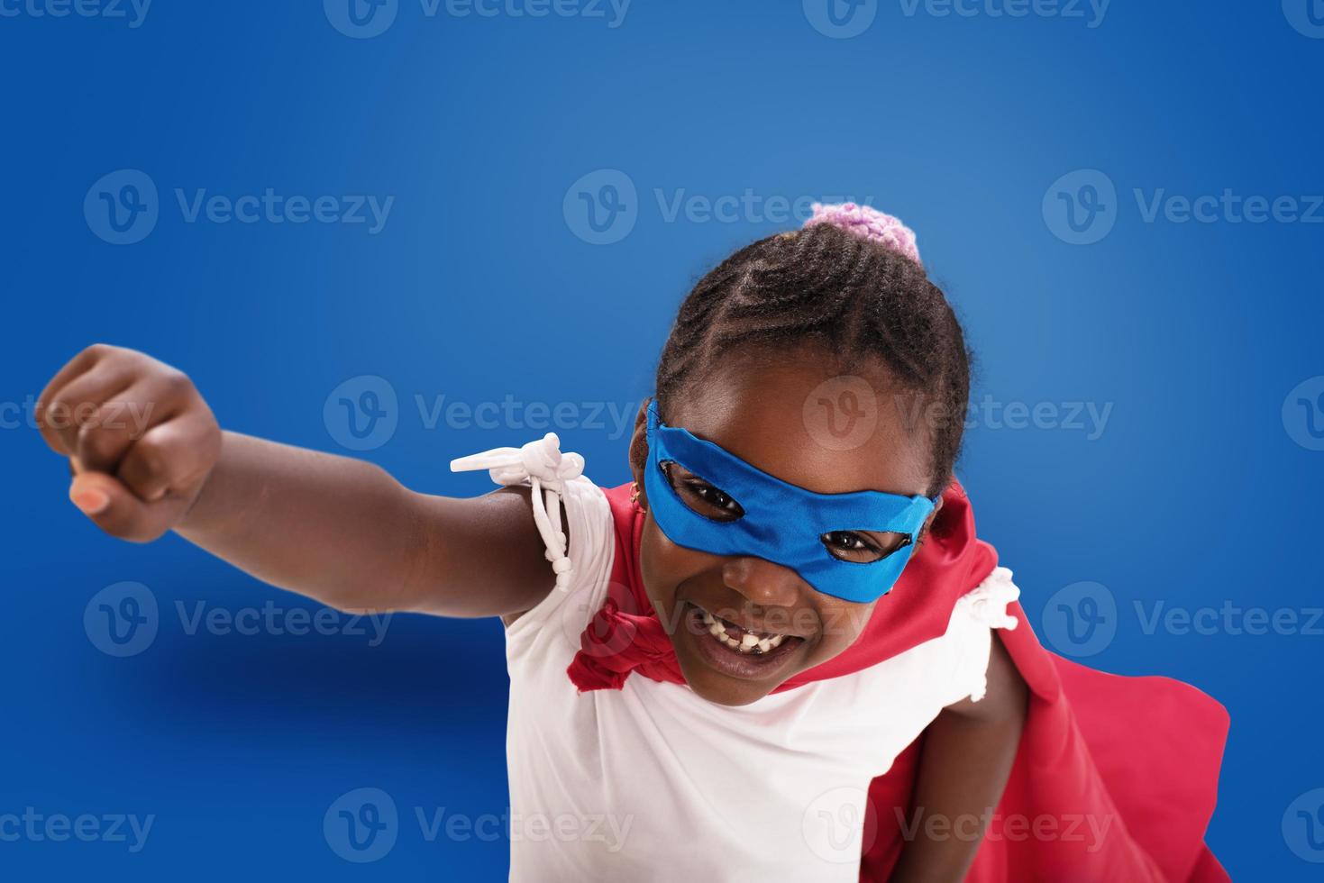 Child acts like a superhero to save the world on blue background photo