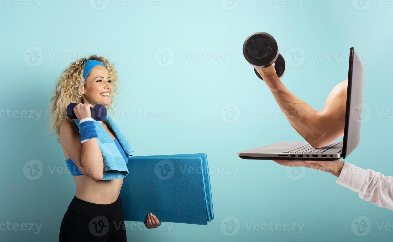 Girl with handlebars ready to start the gym online with a computer. cyan background photo