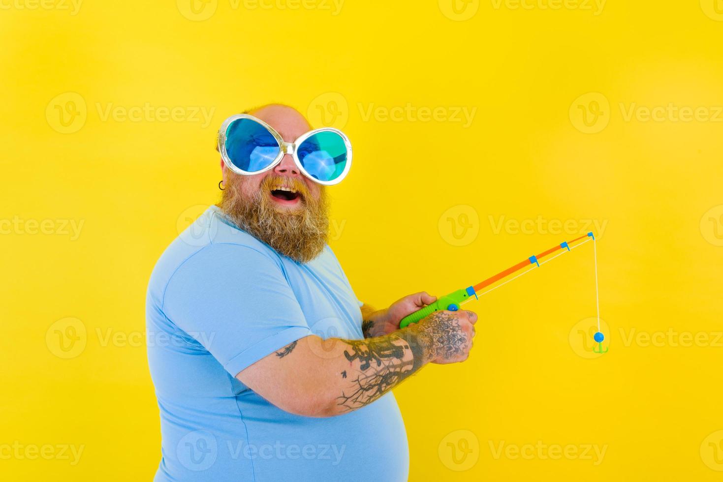 Fat man with beard and sunglasses have fun with the fishing rod photo