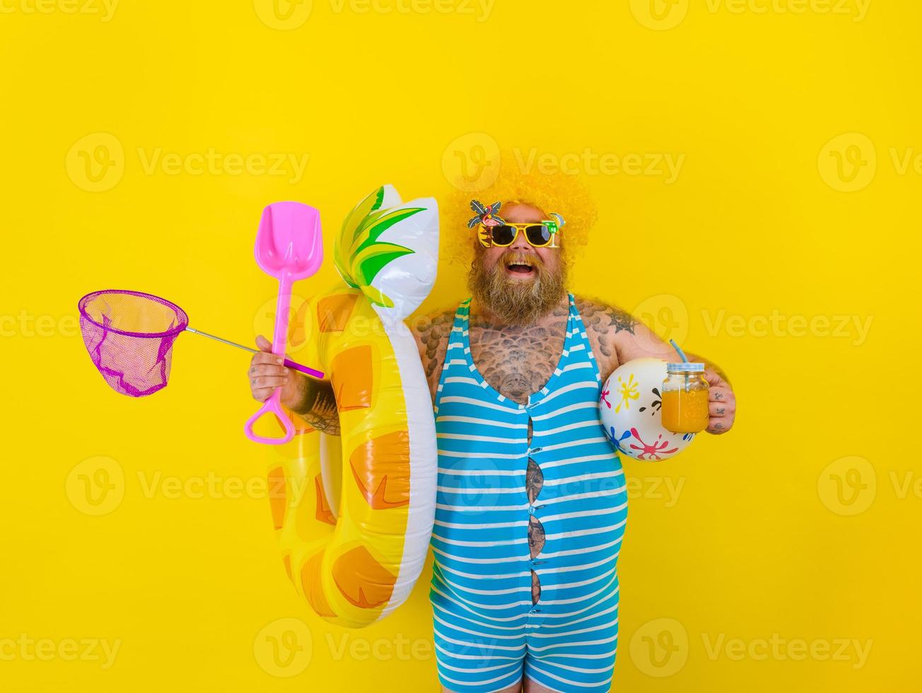 Fat happy man with wig in head is ready to swim with a donut lifesaver photo
