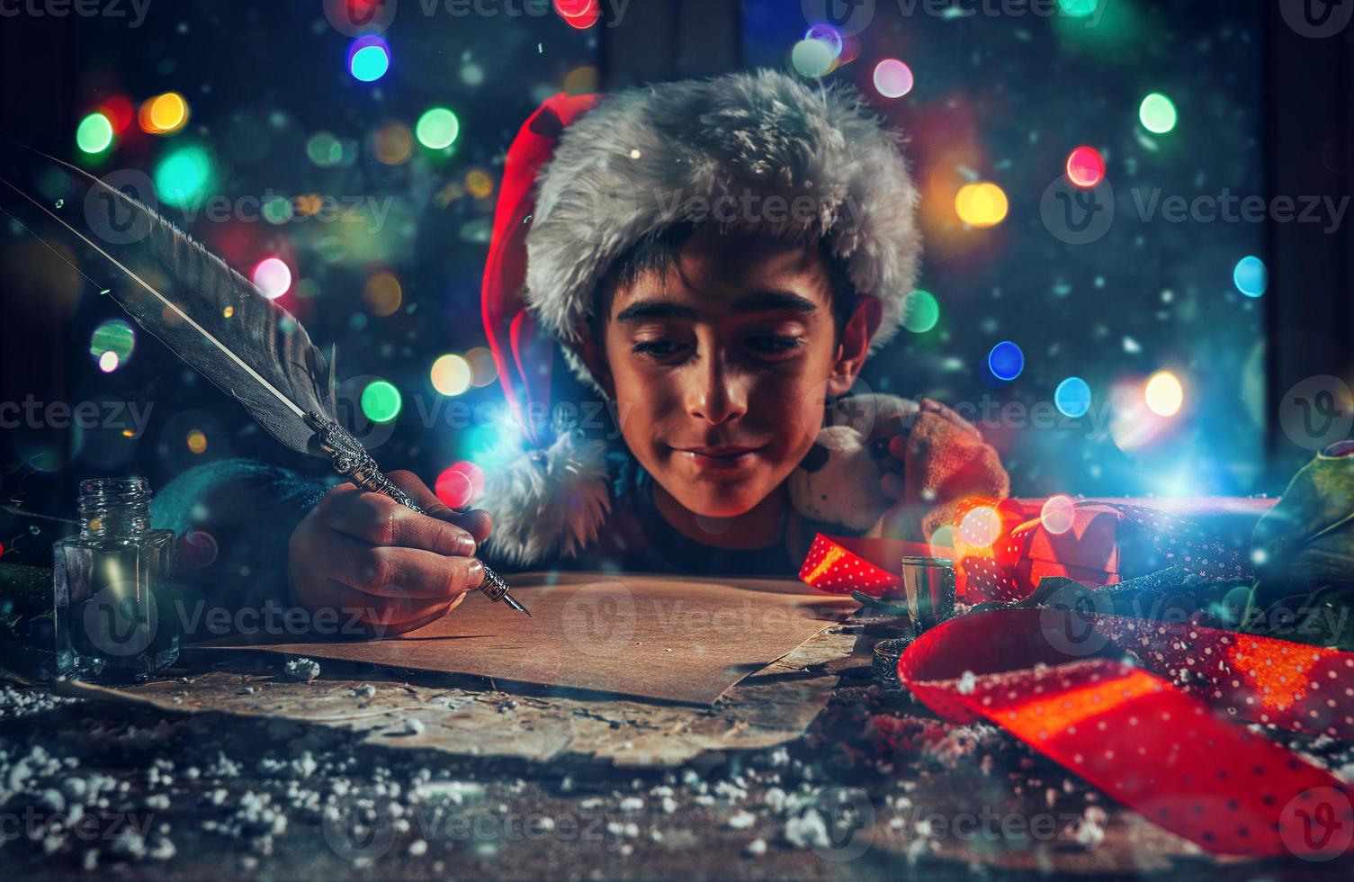 Child with Christmas hat writes a letter to santa claus for gifts photo