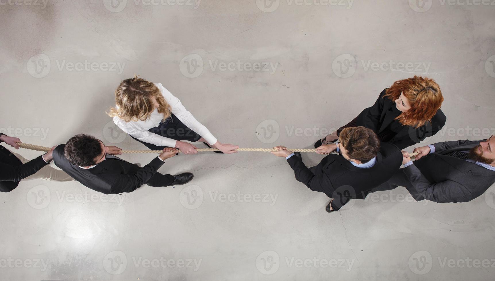 Rival business man and woman compete for the command by pulling the rope photo