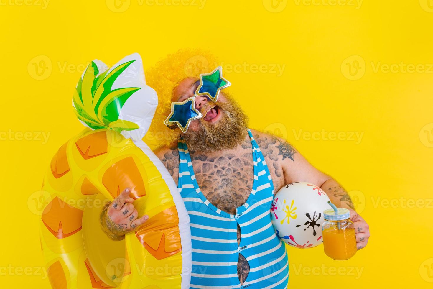 Fat happy man with wig in head is ready to swim with a donut lifesaver photo