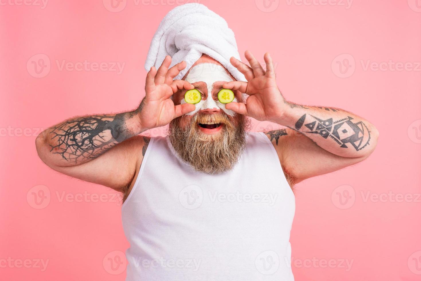 Man with beard acts like a woman and has fun with a facial mask photo