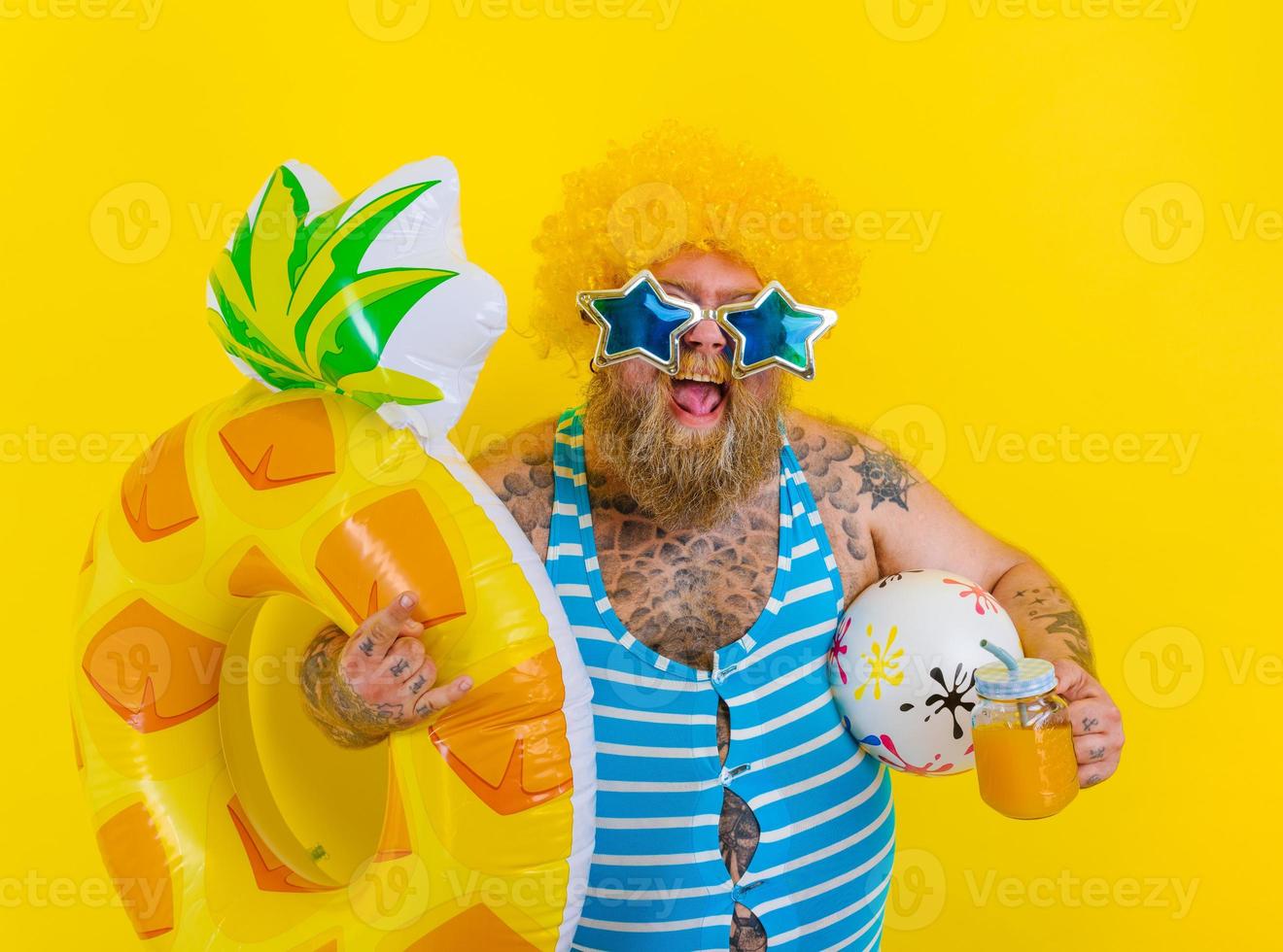 Fat happy man with wig in head is ready to swim with a donut lifesaver photo