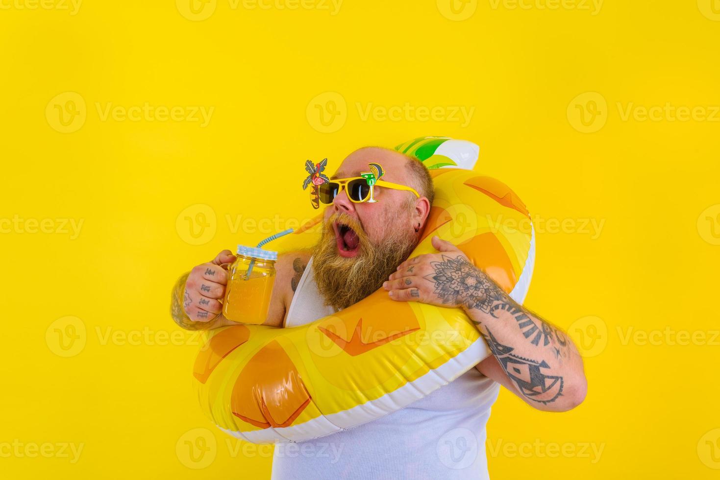 Fat hungry man with wig in head is ready to swim with a donut lifesaver photo