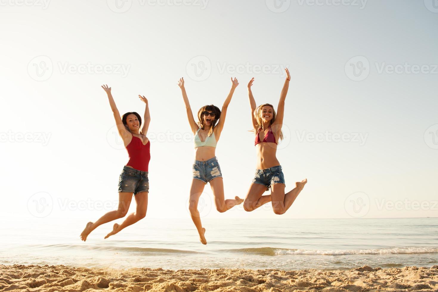 contento sonriente amigos saltando a el playa foto