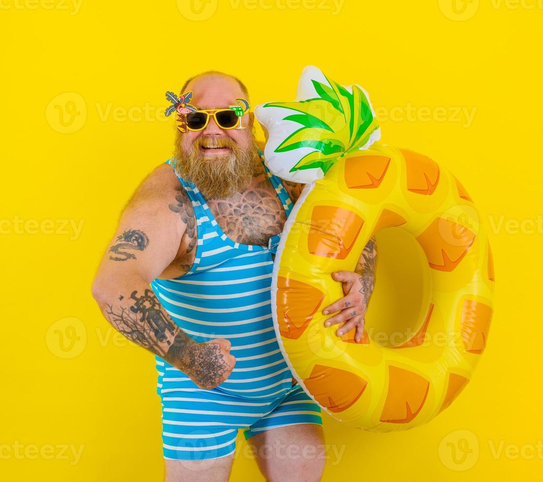 Fat happy man with wig in head is ready to swim with a donut lifesaver photo